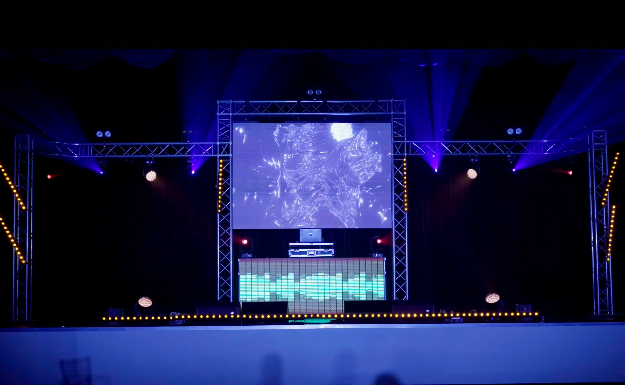 Montaje de DJ Booth con pantalla, truss e iluminación para eventos escolares